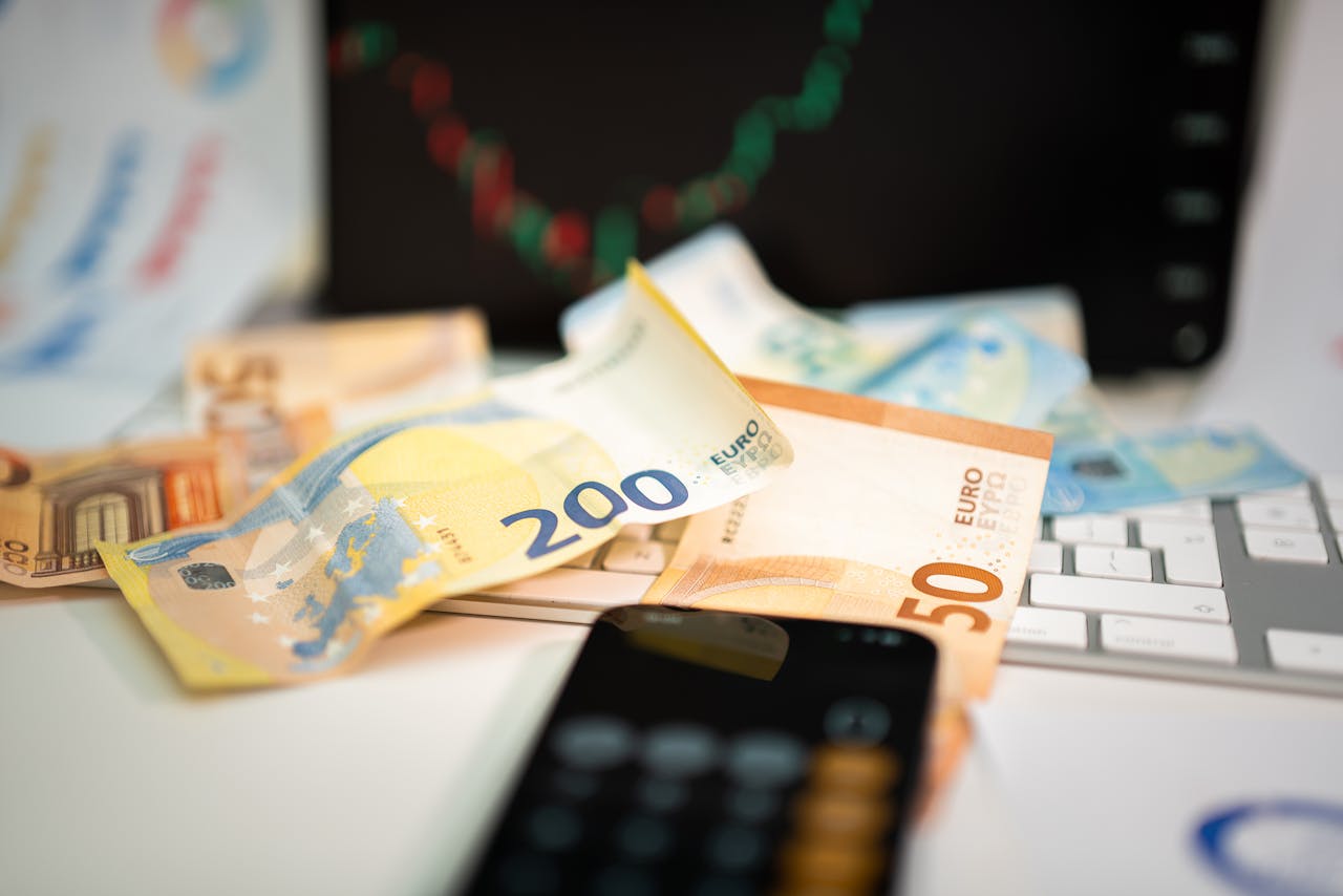 Euro banknotes and smartphone on desk, symbolizing finance and technology in business.